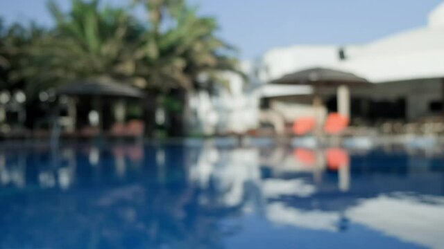 Blue clear water in hotel pool on sunny day. Waves on surface in swimming pool. Nobody. Blue clear water in hotel pool. Pool water close up. Blurred background in 4K, UHD
