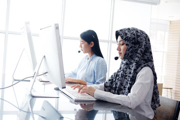Smiling asian Muslim women is call center or secretary operator is wearing a headset and a...