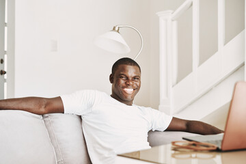 Cheerful man of african appearance at home in front of technology laptop
