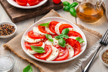 Summer, light, Italian caprese salad with tomatoes, mozzarella cheese, basil and olive oil.