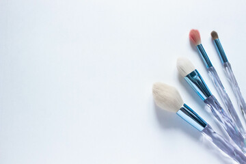 Brushes a flat lay with copy space. Beauty cosmetic makeup product layout. Stylish design. Creative fashionable concept. Cosmetics make-up brushes collection on a white background, top view.
