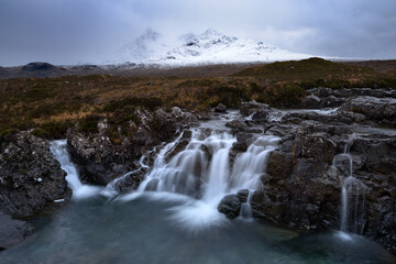 Beautiful waterfall at Sligachan with view of snowcapped Cuillin mountain range, Isle of Skye, UK. 