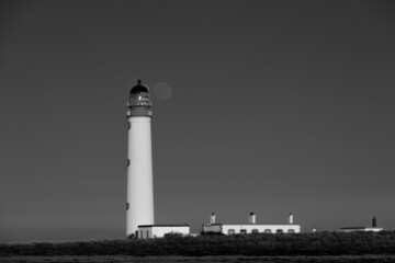 the full moon lines up with the lantern of the lighthouse in mono