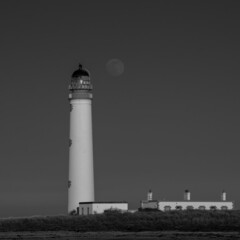 the full moon rising behind a lighthouse in mono