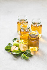 Freshly squeezed juice from green apples in a small glass bottles on a light gray background