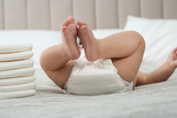 Cute little baby in diaper on bed at home