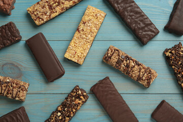 Different tasty protein bars on light blue wooden table, flat lay