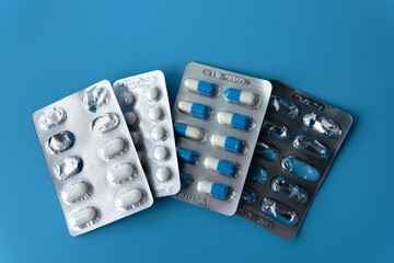 top down view Medicine pills or tablets capsules for antibiotics or antiviral for medical purpose in blister pack on blue isolated background. Healthcare concept