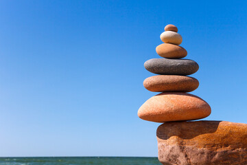 Rock Zen pyramid of colorful stones standing on the edge of a cliff.