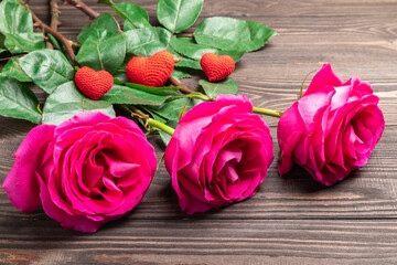 Fototapeta premium beautiful roses and knitted hearts on a wooden background