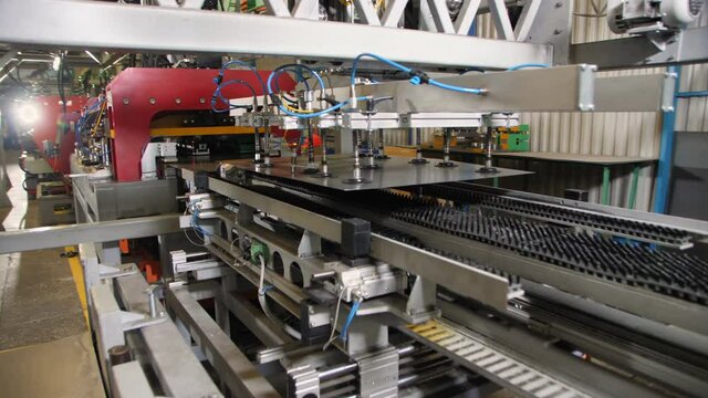 Contemporary automatic production line with metal sheet held by manipulator with vacuum cups in plant workshop close view
