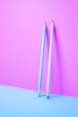 Two pencils concept. Purple and blue pencils split a picture in two different colors