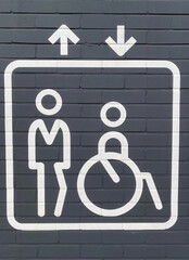 Closeup of isolated white elevator sign on grey wall with disabled person in wheelchair and...