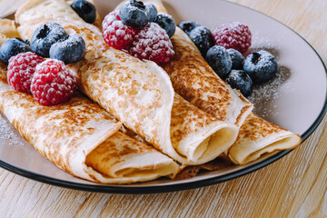 Crepes with berries on wooden background