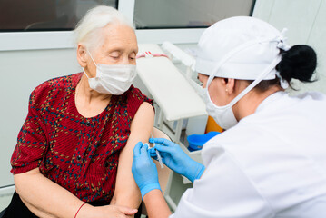 a doctor or nurse injects a drug or vaccine into an elderly woman's shoulder. Vaccination against covid-19, diabetes, insulin.