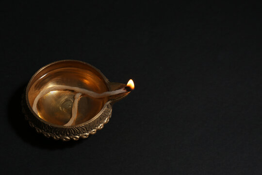 Lit diya on dark background, space for text. Diwali lamp