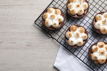 Delicious salted caramel meringue tarts on light wooden table, flat lay. Space for text