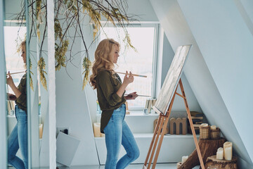 Side view of attractive young woman painting in art studio