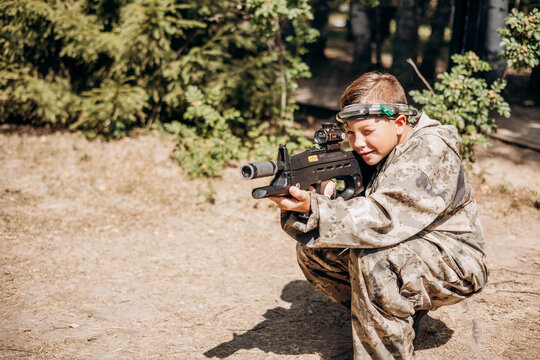 Boy looking into the optical sight a weapon. Children playing laser tag shooting game in outdoor. War simulation game