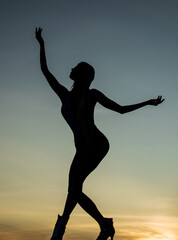 Obraz premium Dancing silhouette of woman ballet dancer in twilight silhouetted on evening sky, ballet