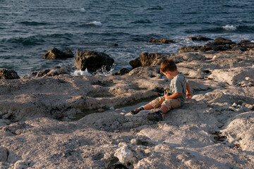 A child is playing on the beach. Rocky shore. Summer evening.