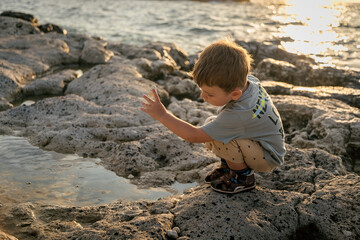 A child is playing on the beach. Rocky shore. Summer evening.