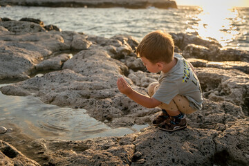 A child is playing on the beach. Rocky shore. Summer evening.