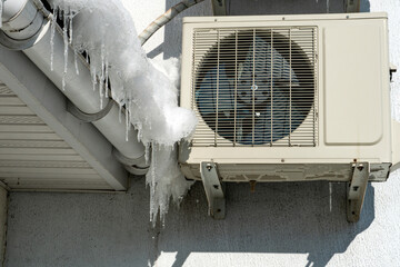 An outdoor air conditioner unit installed on the outer wall of a residential building close-up....