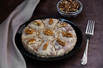 Turkish desserts. sunflower halva with fork and Turkish tea in traditional glass on the wooden table close-up. glass cup of black tea with walnuts on the dark brown background with copy space.
