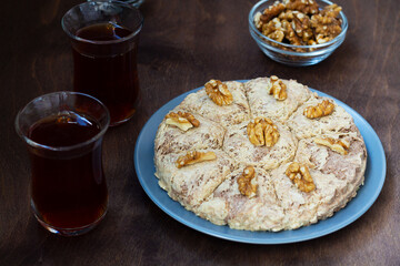 Turkish cuisine. sunflower halva and Turkish tea in traditional glass on the wooden table close-up. two glass cups of black tea with walnuts on the dark brown background with copy space.