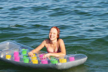 joyful smiling teenage girl bathes with air mattress in the sea