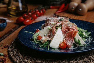 meat with vegetables and herbs salad Italy ruccola cherry tomatos Parmigiano cheese prosciutto