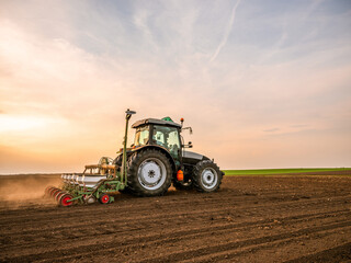 Farmer seeding, sowing crops at field. Sowing is the process of planting seeds in the ground as part of the early spring time agricultural activities. - obrazy, fototapety, plakaty