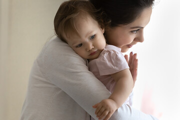 Loving happy young Caucasian mother hug cuddle cute little baby daughter enjoy time at home together. Smiling caring mom caress lull small newborn toddler kid child. Motherhood concept.