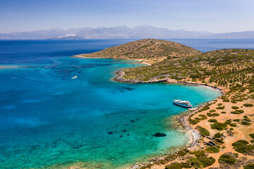 Aerial view of a crystal clear blue ocean and hot, summer landscape with tourist boats (Crete, Greece)