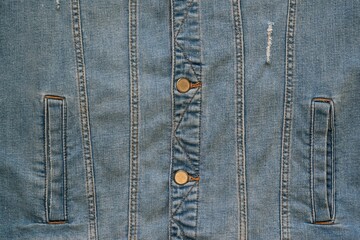 the front part with the lower pockets of a worn blue denim jacket is a closeup