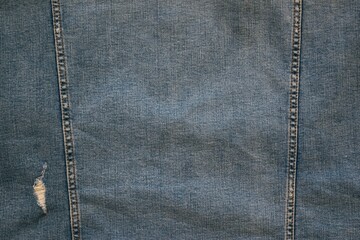 one small ragged hole and two vertical seams on old blue denim for background or wallpaper - 449696091