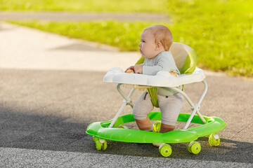 A little boy learns to walk with the help of a walker