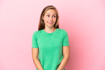 Young English woman isolated on pink background making doubts gesture looking side