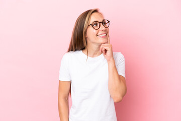 Young English woman isolated on pink background thinking an idea while looking up