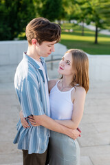 Fototapeta premium Couple of teenagers holding hands and hugging in the park. The first love