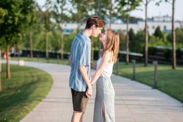 Naklejka premium Couple of teenagers holding hands and hugging in the park. The first love