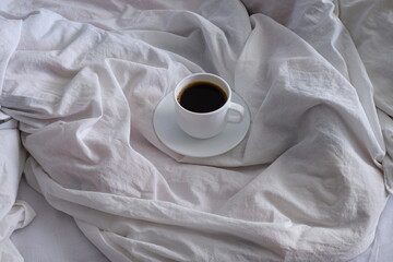 A cup of black coffee in bed. Interior. Cosiness.