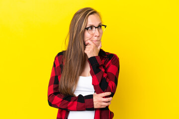 Young English woman isolated on yellow background having doubts and thinking