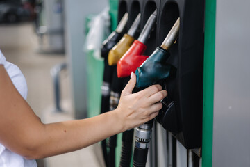 Close-up of a women's hand using a fuel nozzle at a gas station. Petrol station concept. Filling station at petrol gasoline