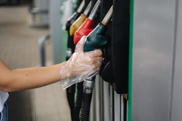 Close-up of a women's hand using a fuel nozzle at a gas station. Petrol station concept. Filling...