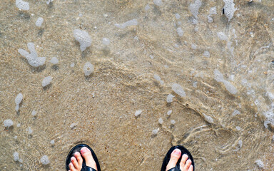 Feet on the sand and waves on the sea beach