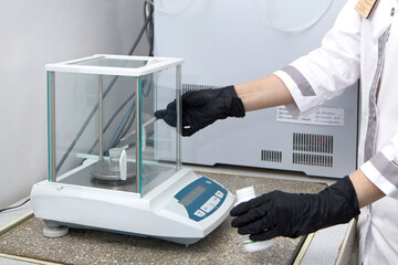 Scientist weighing chemicals by digital scales in grams in chemical laboratory