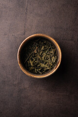 selective focus, natural green leaf tea. brewing in a clay bowl. vertical angle, macro. on a dark background. for menus and cafes