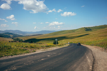 Fototapeta premium A highway among green hills. Summer. Blue sky and green grass.
